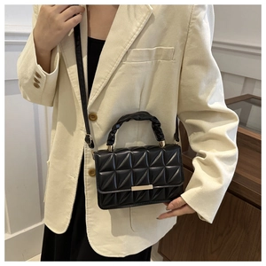 Detail of black quilted shoulder bag with cloud-like handle and gold metal clasp