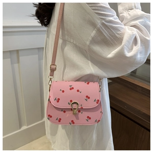 Detail showing pink crossbody bag with red cherry pattern and gold metal buckle