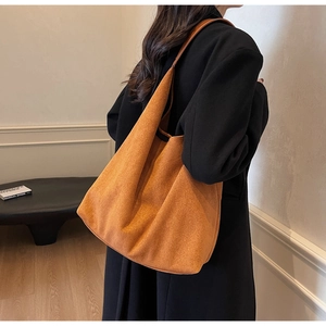 Side view of a large caramel suede tote bag worn on shoulder for autumn winter style