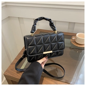 Detail of quilted black leather crossbody bag with pleated handle and gold hardware