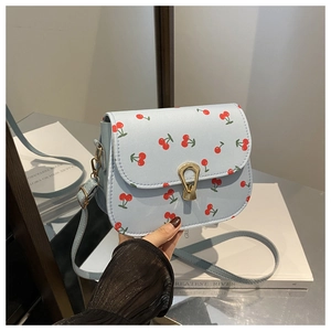 Detail of light blue crossbody square bag featuring red cherry prints and gold metal clasp