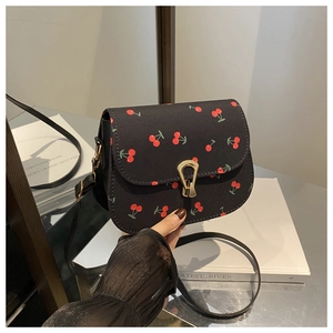 Close-up of black crossbody bag featuring vibrant red cherry print and gold metal clasp