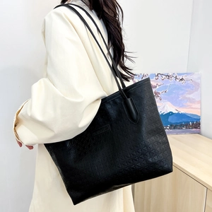 Large black tote bag with embossed star patterns and slim leather shoulder straps