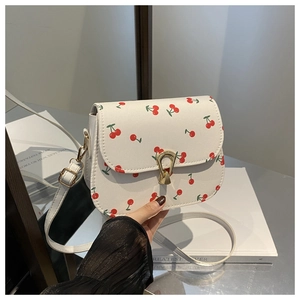 Close-up of white crossbody bag with red cherry print and golden twist-lock closure