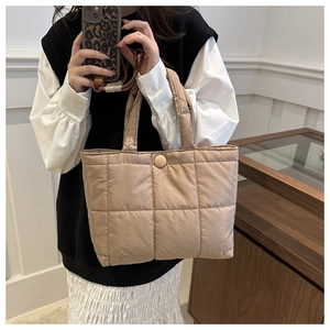 Detail of beige quilted tote bag showing padded fabric texture and button closure