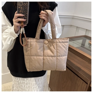 Detail view of the champagne gold quilted tote bag with wide handles and snap closure