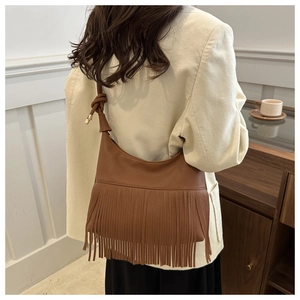 Detalle del bolso hobo de cuero marrón con flecos largos y correa para el hombro anudada