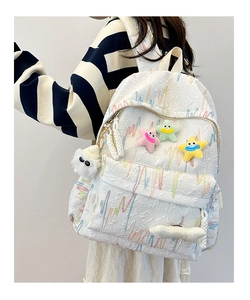 Detail of white textured backpack with colorful embroidery and plush star charms