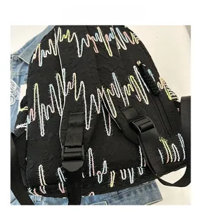Close-up of adjustable straps and colorful wave embroidery on black backpack fabric