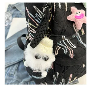 Close-up of cute white plush monster and pink star charms on a black backpack