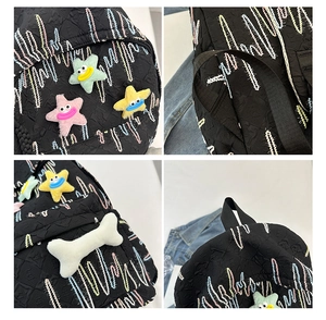 Detail of black nylon backpack with colorful wave embroidery and plush star patches