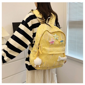 Detailed view of yellow jacquard backpack with cute star charms and plush ball accessory
