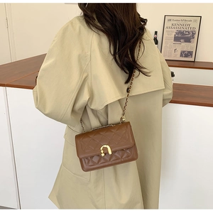 Detailed view of the brown quilted leather crossbody bag with golden U-shaped clasp