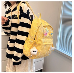 Side view of a bright yellow textured school backpack with colorful star patches