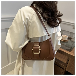 Macro detail of dark brown leather underarm bag featuring a glossy gold square buckle