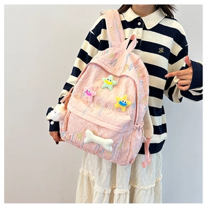 Detailed view of pink crinkled backpack with cartoon star patches and plush bone charm