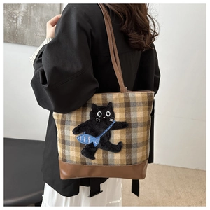 Gros plan d'une broderie de chat noir sur un sac cabas à carreaux porté par un mannequin