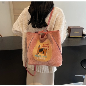 Detailed shot of pink corduroy tote bag featuring cat illustration and slender leather straps