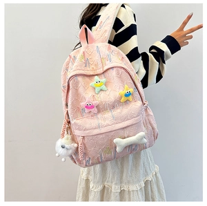 Detailed view of pink jacquard backpack with star patches and plush bone charm