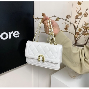 Detail of white quilted leather bag showing gold horse-bit clasp and chain strap