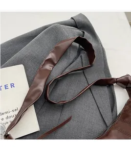 Detail of a brown PU leather shoulder bag featuring a wide strap and zipper closure