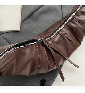 Detailed macro shot of the smooth silver zipper and stitching on the brown crescent bag