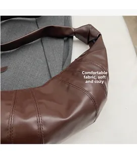 Detailed macro view of dark brown crescent bag with stitching and soft texture
