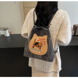 Detail view of a dark grey corduroy backpack with cat patch and embroidery on a model