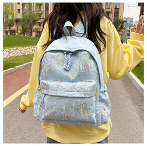 Detail of light blue backpack with jacquard texture and colorful wavy embroidery work