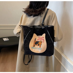 Detail of black corduroy tote bag with cat embroidery worn on model's shoulder