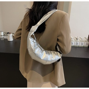 Detail of silver crescent shoulder bag with vertical pleats worn by a model
