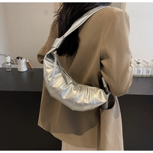 Detailed view of silver pleated crescent bag worn as a shoulder bag on a model