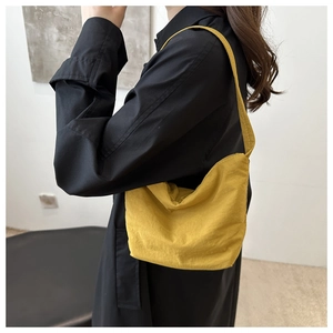 Bright yellow nylon shoulder bag detail showing the smooth zip closure and texture