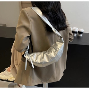 Detail of silver metallic crescent bag with pleated texture and stylish knotted shoulder strap