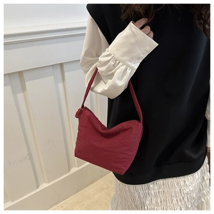 Close-up of a minimalist burgundy crescent underarm bag with smooth zipper detail
