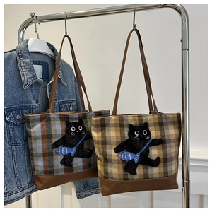 Détail du sac cabas à carreaux avec écusson de chat noir brodé et bandoulières en cuir