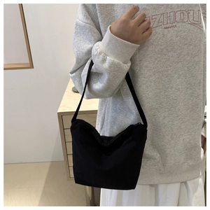 Minimalist black canvas underarm bag shown on shoulder for daily commuting style