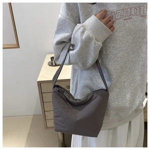 Detailed view of grey hobo bucket bag styled on shoulder with minimalist casual aesthetic