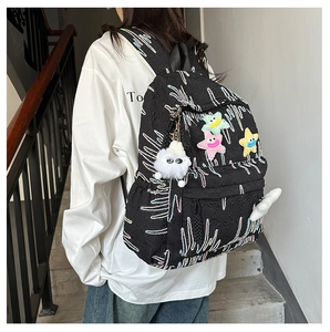 Close-up of black backpack featuring colorful star patches and side fur ball detail