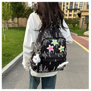 Detail of black canvas backpack featuring wave embroidery and colorful plush stars