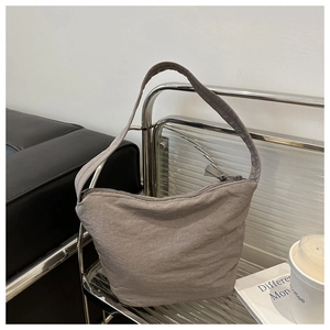 Detailed close-up of grey canvas hobo bag texture and zipper on metal display stand