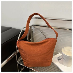 Detail of orange textured nylon bucket bag with integrated strap on industrial metal rack