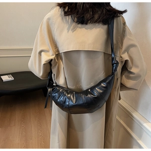 Detailed view of black pleated crossbody bag with decorative knots on shoulder strap