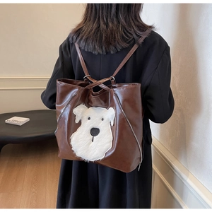 Detail of dark brown leather backpack featuring a cute plush dog patch on the back