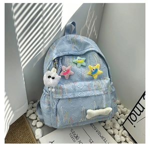 Close-up of light blue backpack with colorful embroidery and cute plush star pendants
