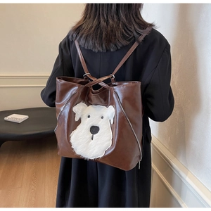 Detailed view of brown leather backpack with cute plush dog patch being worn by a model