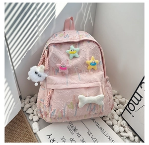 Pink fabric backpack detail showing textured weave and cute plush star charms