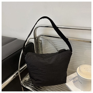 Detailed texture of black nylon underarm bucket bag with a minimalist trapezoid design