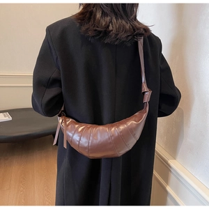 Detail of dark brown quilted croissant bag with knotted shoulder strap worn by model