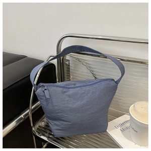 Detail view of fog blue minimalist nylon bucket bag with smooth zipper on urban background
